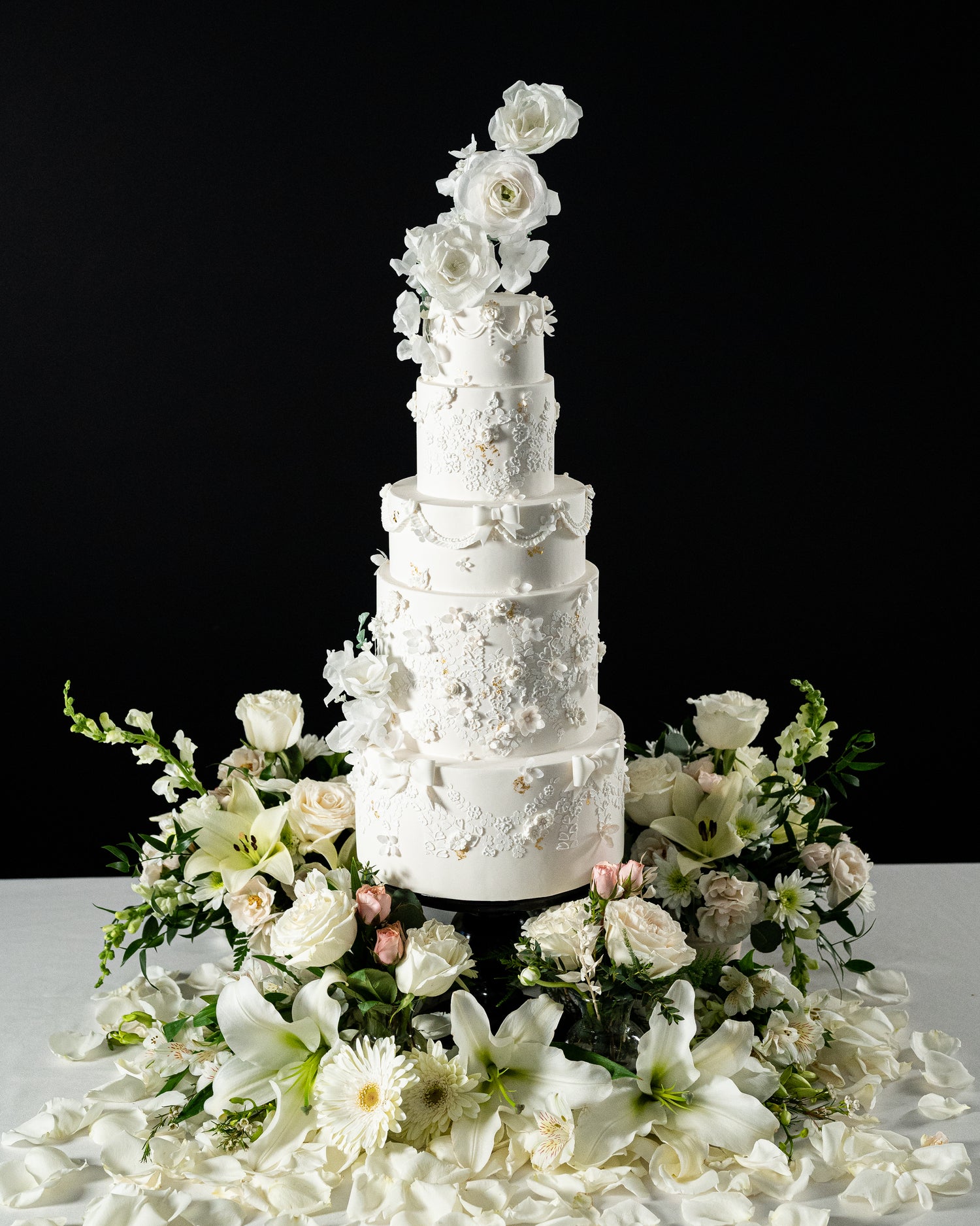 tall floral black and white classic elegant wedding cake by sugar nursery with ranunculus and roses