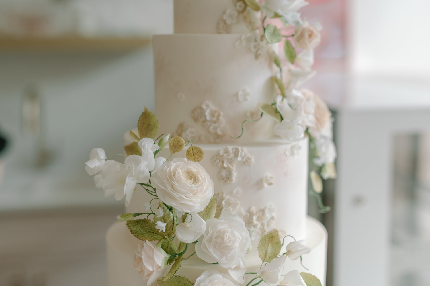 White wedding cake with floral decorations in a blurred indoor setting